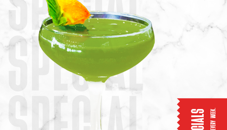 The Swamp, a green tequila cocktail garnished with basil and citrus.